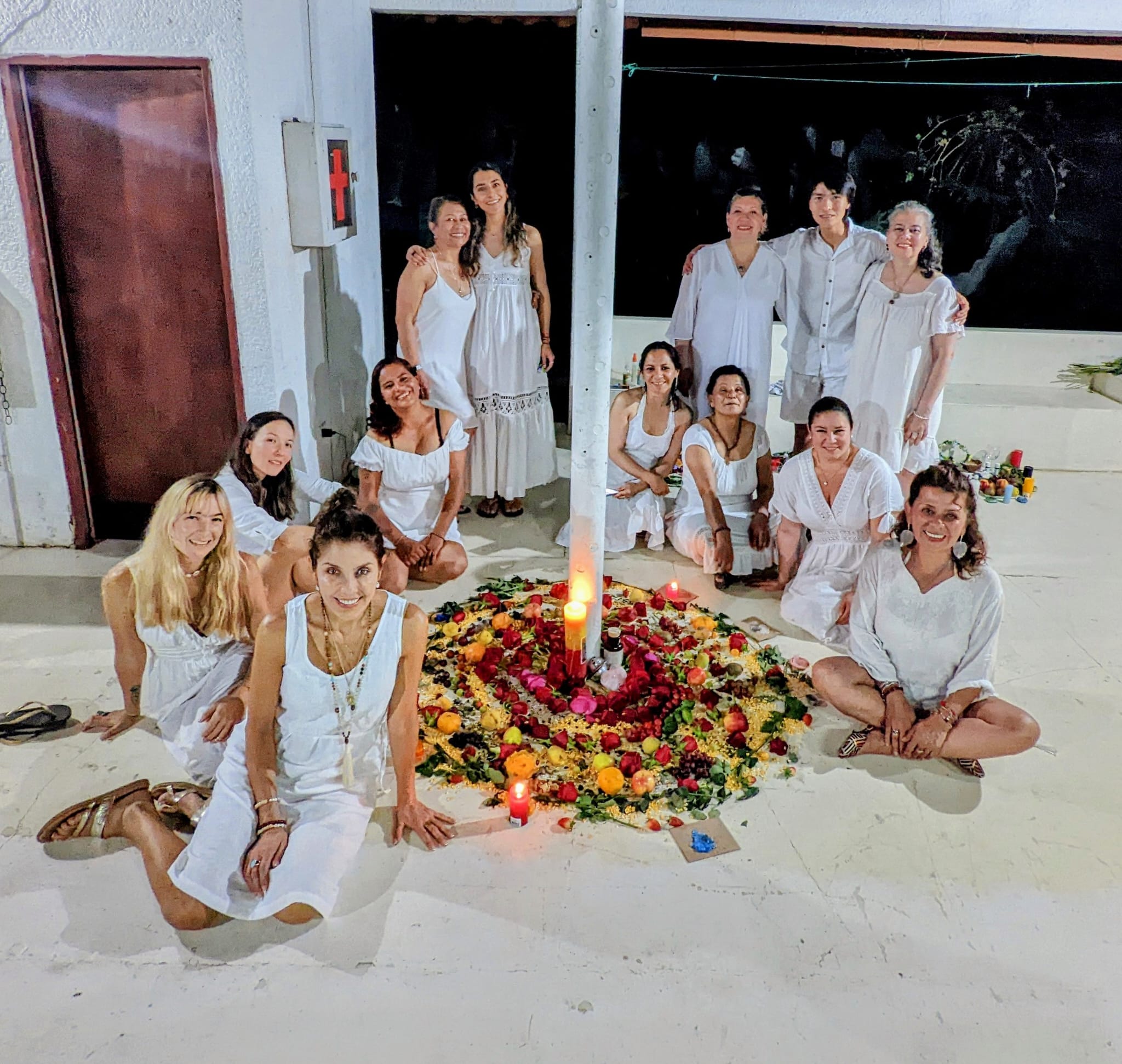 Participantes de un encuentro de Plenitud & Armonía reunidos alrededor de una composición de flores.
